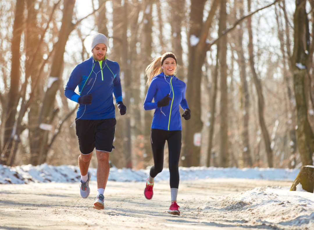 Couple in winter running together in nature Young couple in the winter running together in nature
