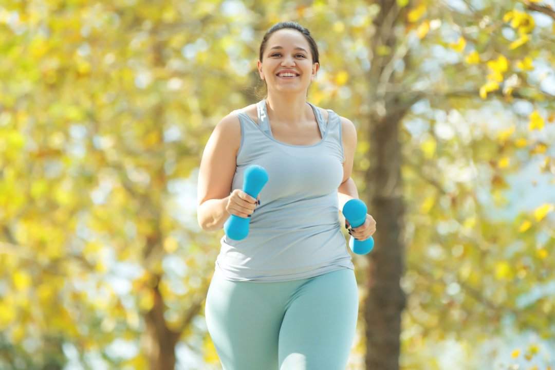 Beautiful mature African American woman smiling and laughing. Smiling curvy young woman jogging in a park.